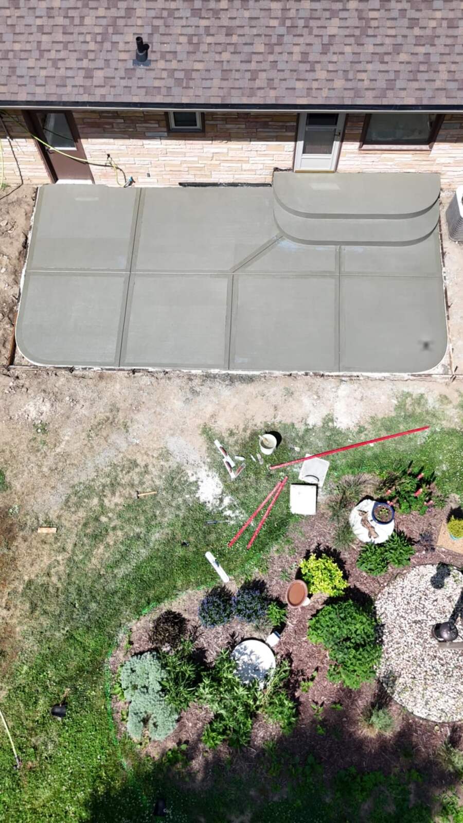 Aerial view of a new concrete patio with steps next to a landscaped bed