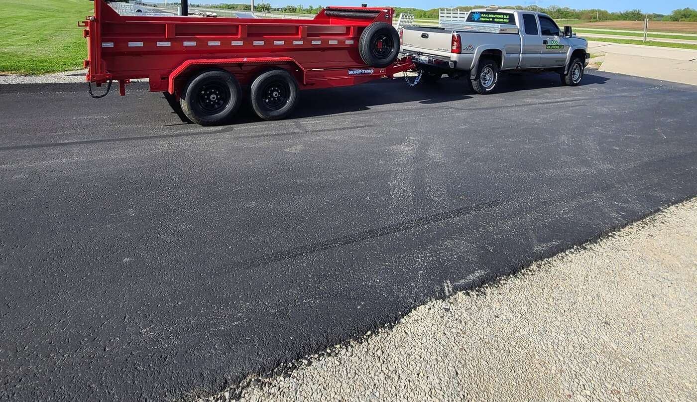 RAH Solutions pickup truck towing a red dump trailer on a paved lot